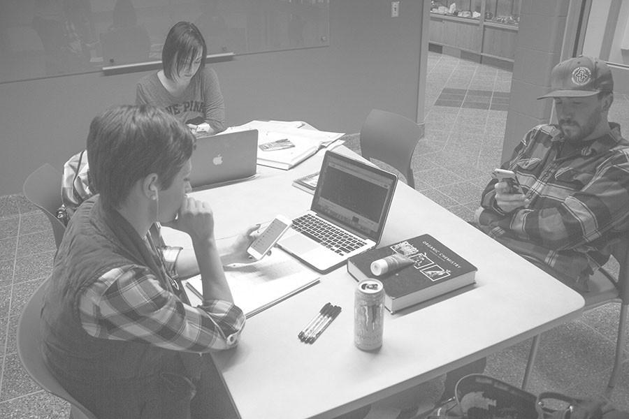 Students sit and text on their phones while studying in Jonas cubicles