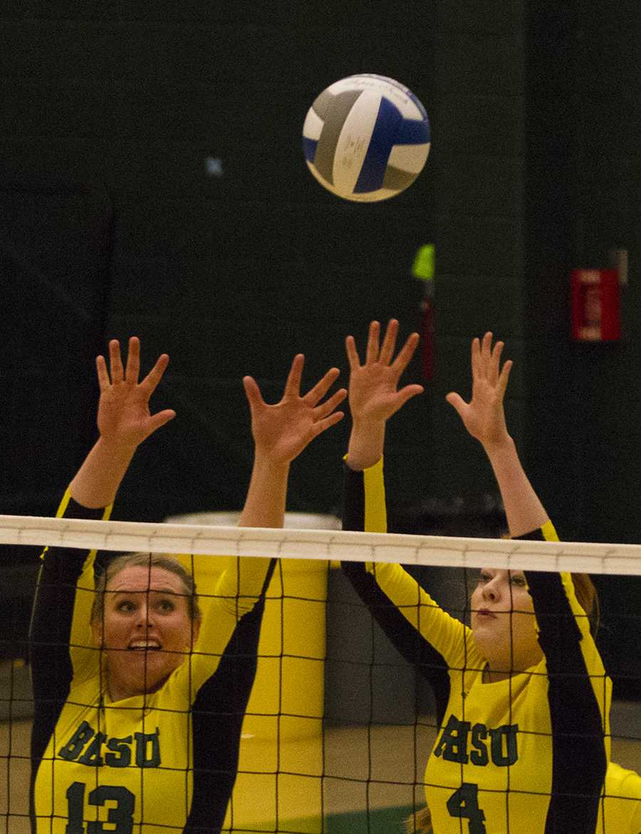 Shelby Mayer (13) and Kenzie Kazmer (4) go up to block a shot during their Oct. 10 game with Regis.