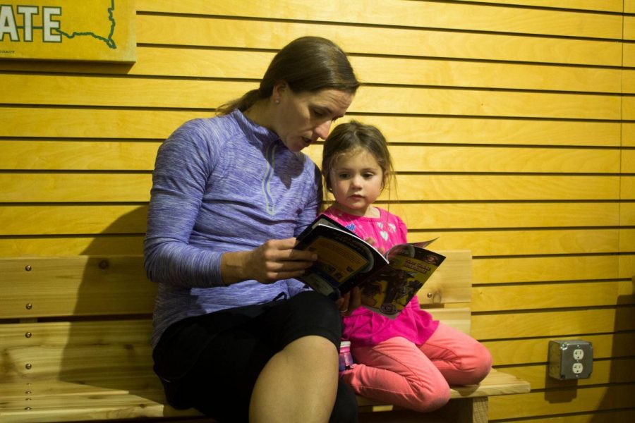 The parents start reading to their children while waiting for the event to begin