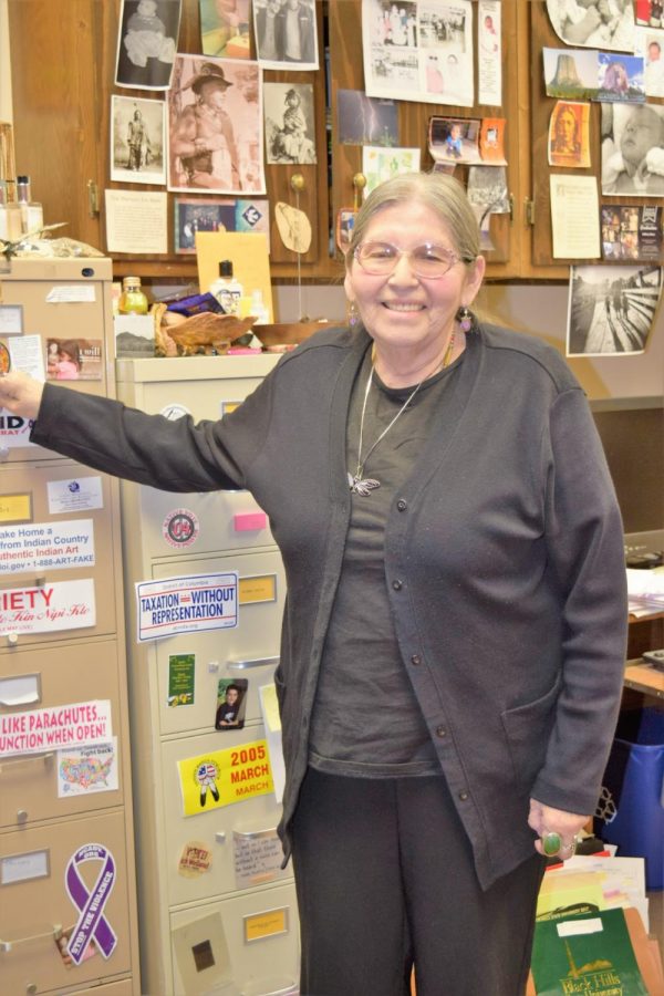 Jace DeCory. BHSU  American Indian Studies Assistant Professor stands in her office, surrounded by over three-decade legacy of materials. 