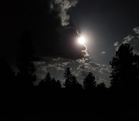 Full moon peaks out from behind the clouds in the Black Hills. 