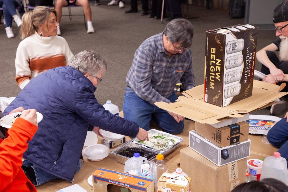 Members of “lower class” at Oxfam Hunger Banquet eating rice and beans off floor.